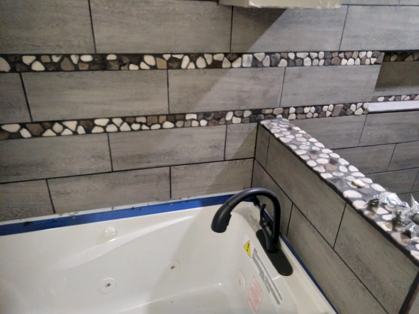 Finished bathroom tile with stone accent detail around a tub